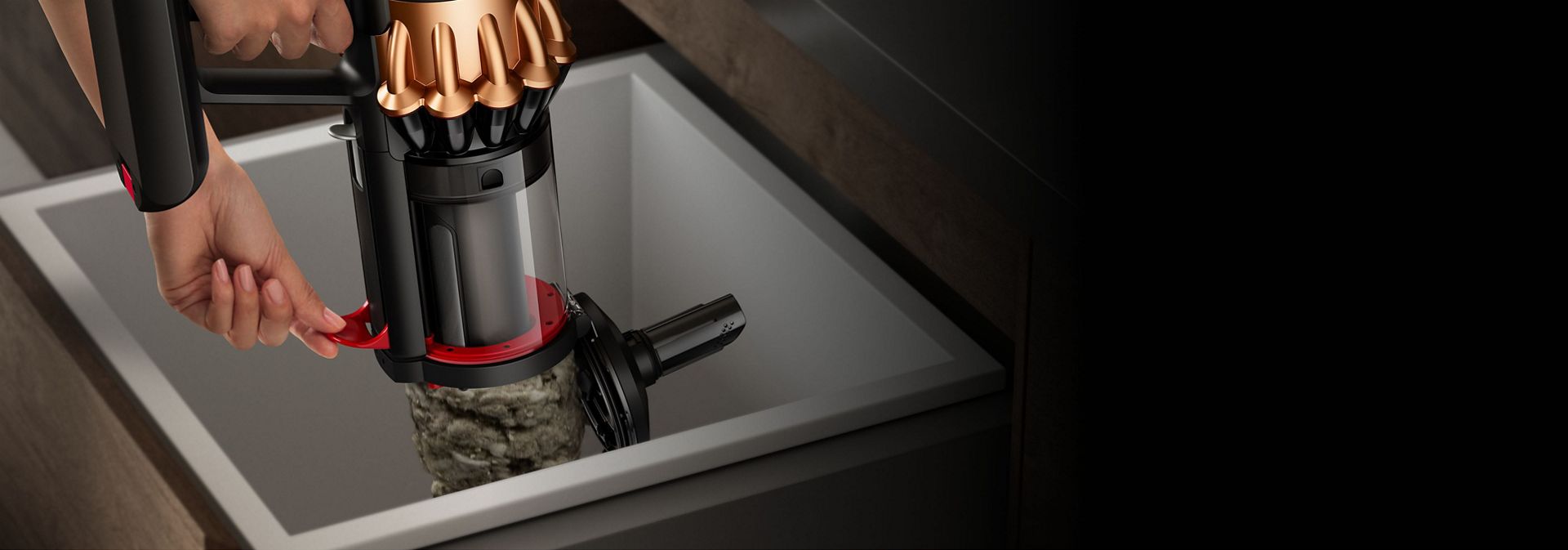 شخصٌ يقوم بتفريغ مع التنظيف بالمسح للأتربة الموجودة في حاوية مكنسة Dyson Piston Animal - باستخدام الذراع الموجود على جانبها.