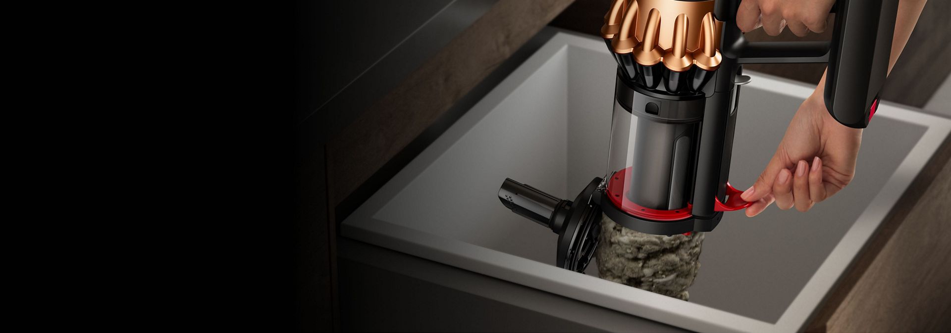 A person wipe-clean emptying the dirt inside the bin of the Dyson Piston Animal vacuum - using the lever on its side.