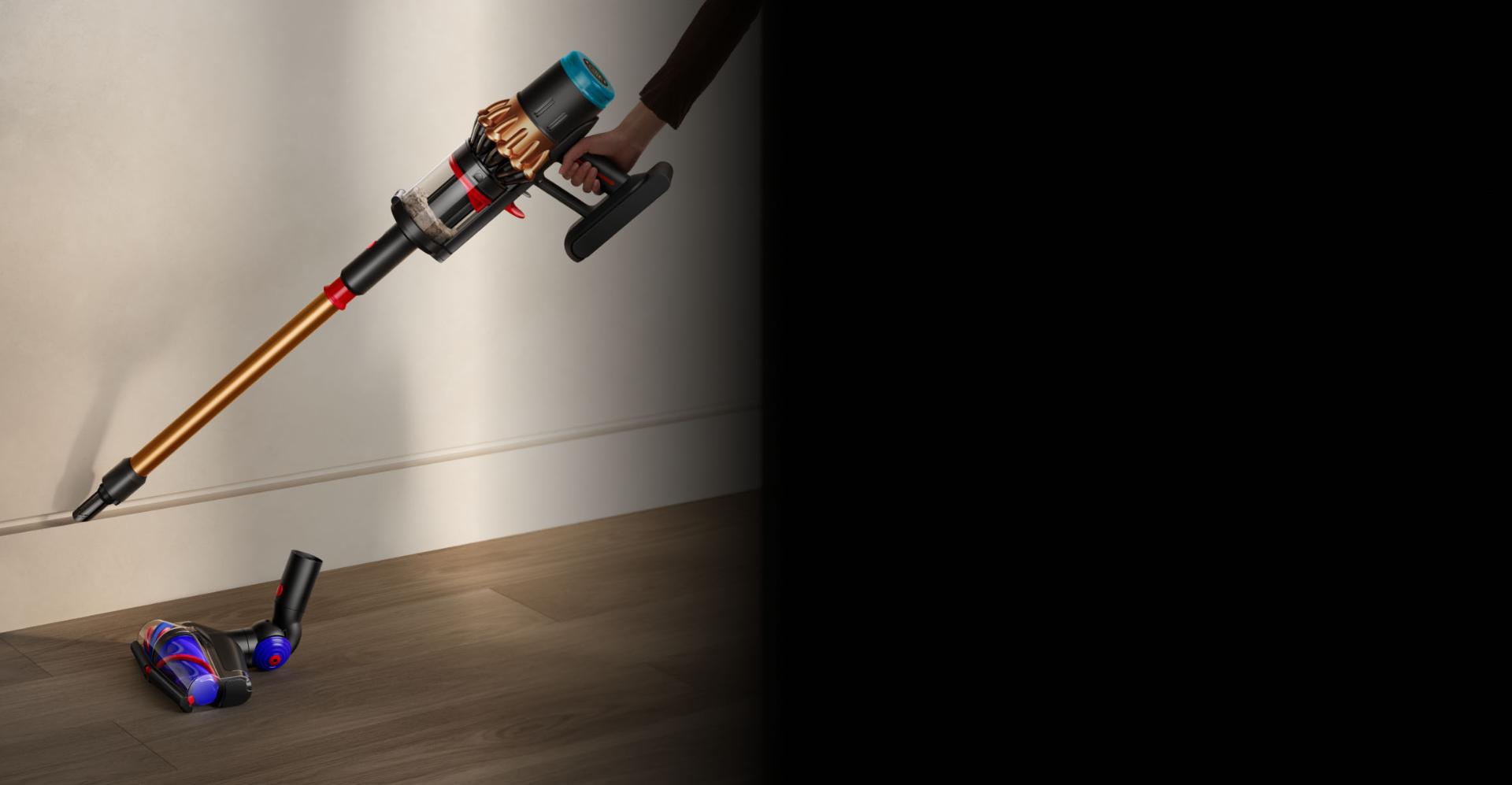 أداة العصا الخاصة بمكنسة Dyson Piston Animal بينما تُستخدَم لتنظيف حافة لوح إزار حائط.