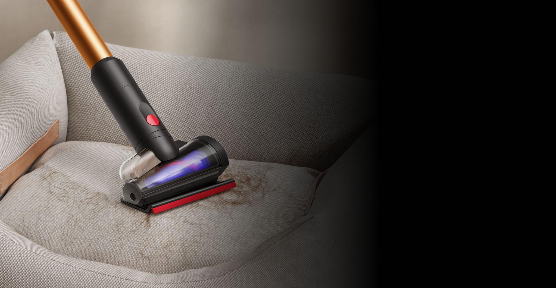 أداة تنظيف الأركان المُدمجة بمكنسة Dyson Piston Animal بينما تُستخدَم لتنظيف الأماكن حول الطاولة.