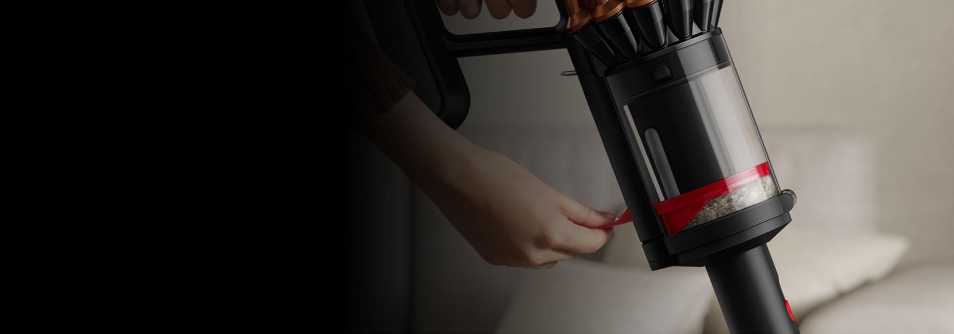 A person compressing dirt inside the bin of the Dyson V16 Piston Animal vacuum.