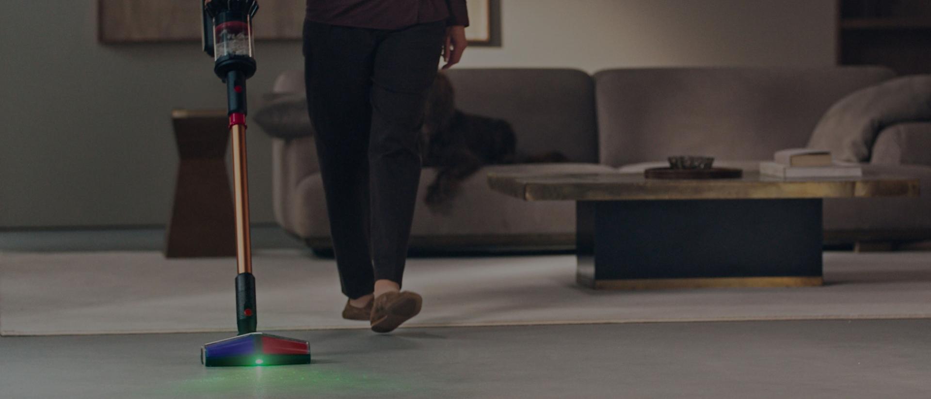 O persoană care folosește aspiratorul fără fir Dyson VS16 Piston Animal cu capul de curățare All Floor Cones Sense.