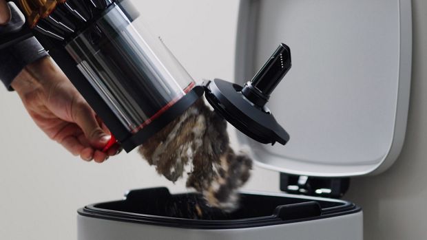 The bin of the Dyson DS60 Piston Animal vacuum is emptied.