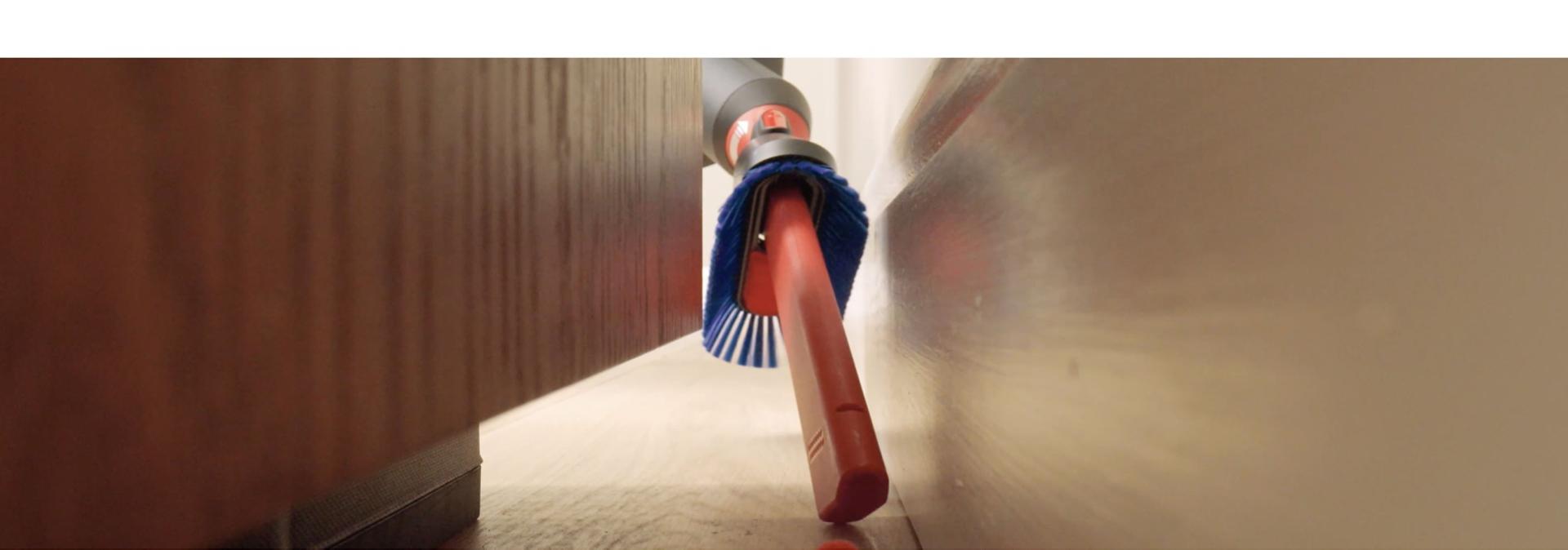 The Awkward gap tool 2.0 is used to clean debris from behind a cabinet.