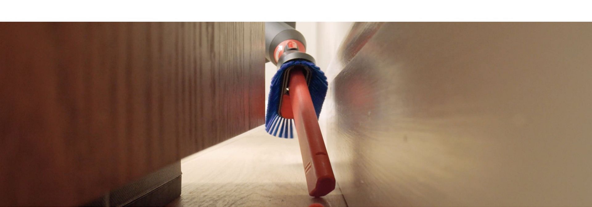 The Awkward gap tool 2.0 is used to clean debris from behind a cabinet.