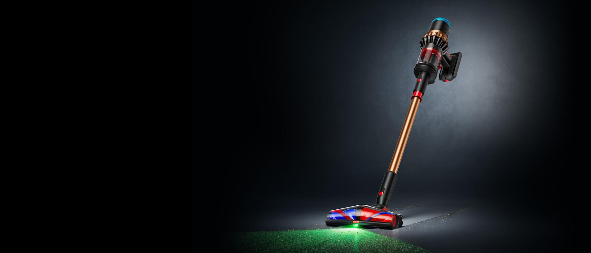 The Dyson Piston Animal cordless vacuum cleaner upright on a dark background, illuminating a hard floor.