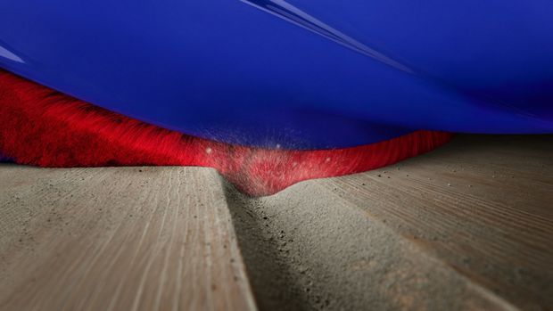 Close-up of the Conical head’s brush bar as it cleans into a crevice on a hard floor.