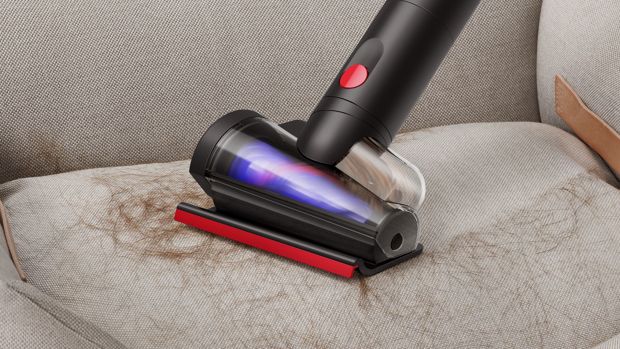 Dyson Hair screw tool 2.0 used to remove shed fur from a pet bed.