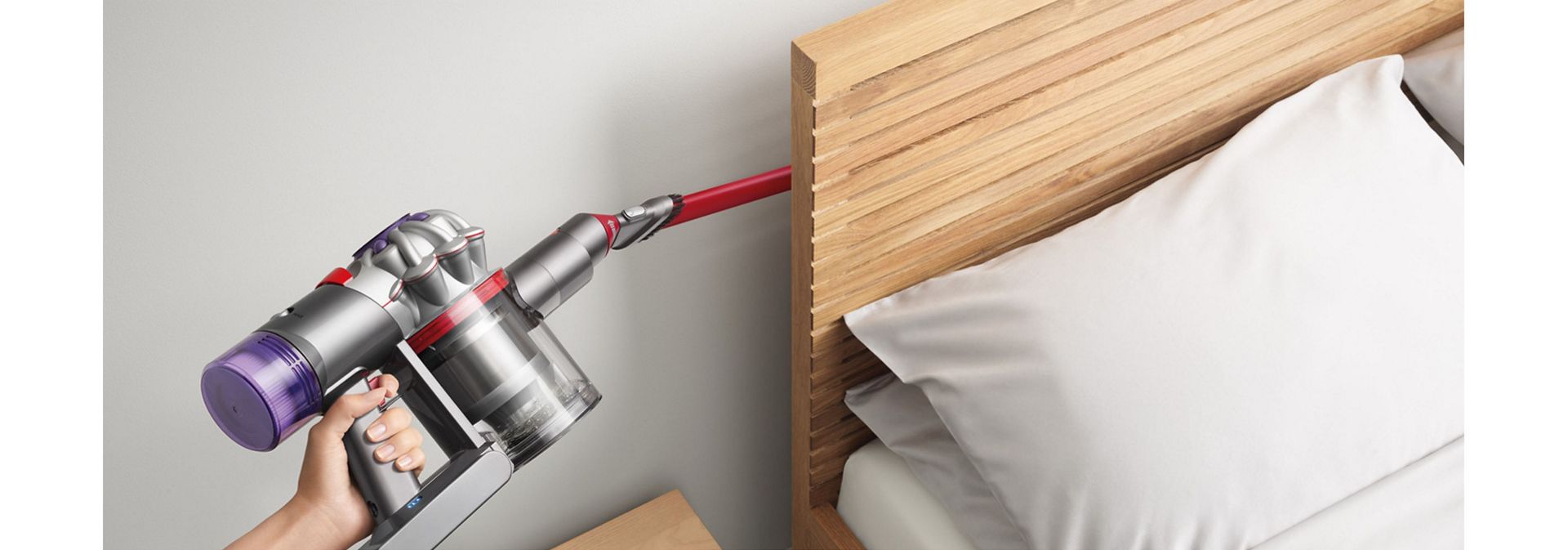 Dyson V8 Focus Clean handheld vacuum used to clean behind a bed.