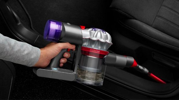 Dyson V8 Focus Clean handheld vacuum used to clean inside a car.