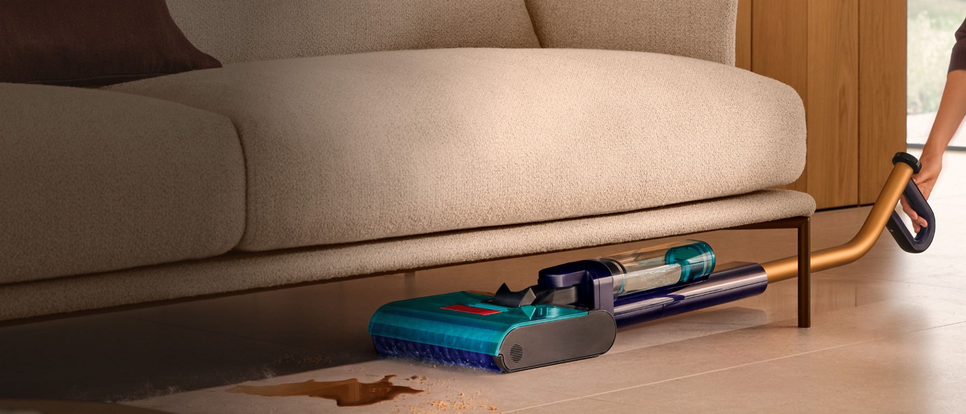 The Dyson Clean+Wash Hygiene hard floor cleaner used to clean under a low sofa.