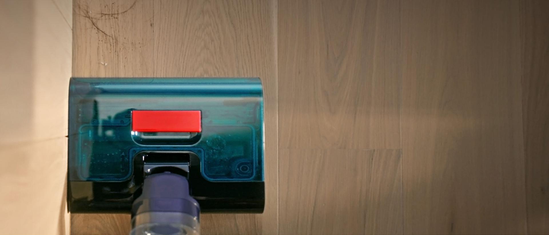 يُنظِّف جهاز تنظيف الأرضيات الصلبة Dyson Clean+Wash Hygiene حتى حافة الجدار.