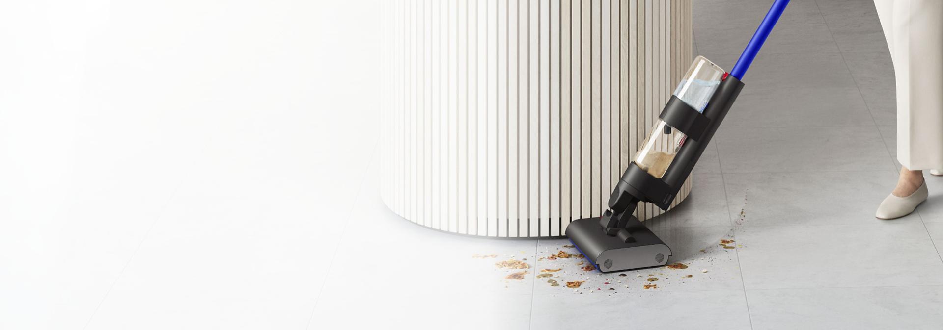 Wysokoobrotowy mop elektryczny Dyson WashG1 w trakcie czyszczenia podłogi wokół wyspy kuchennej.