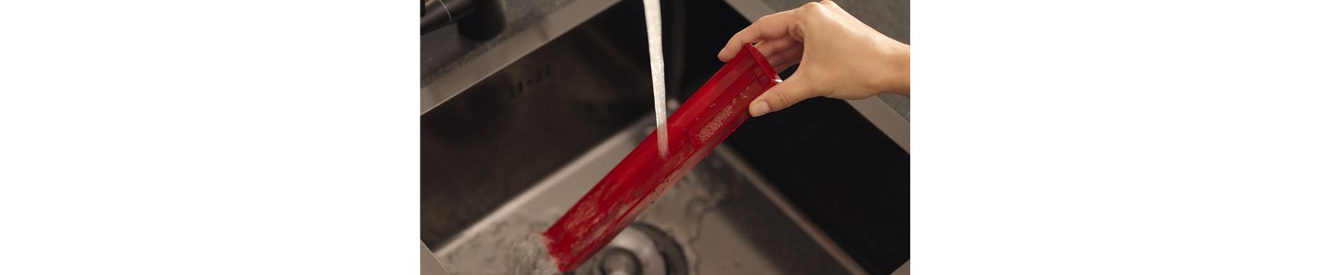 Baki kotoran dibilas di bawah air mengalir.