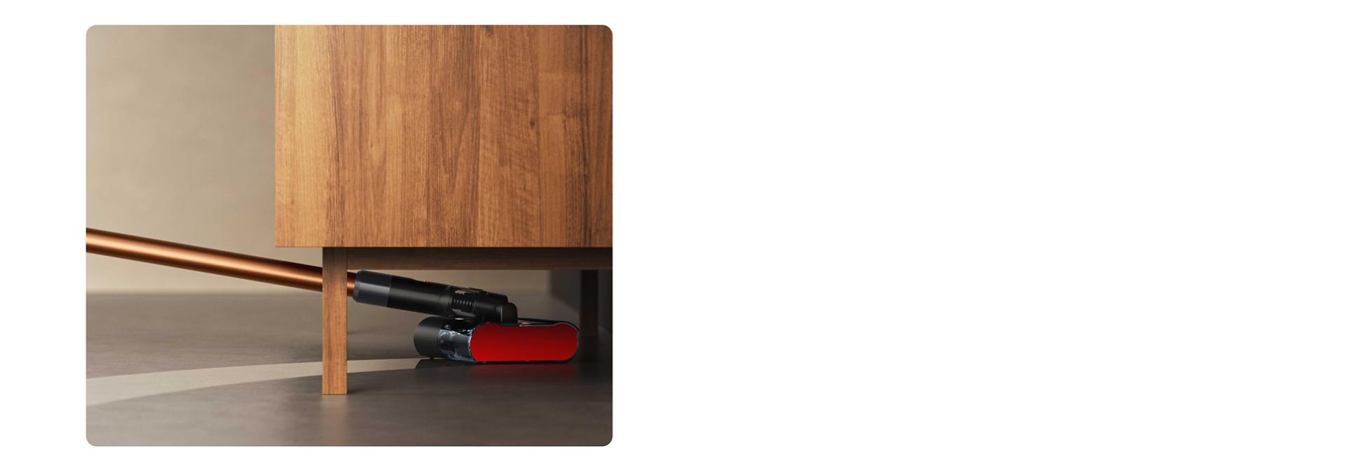 A Dyson PencilWash készüléket takarításra használják egy alacsony szekrény alatt.