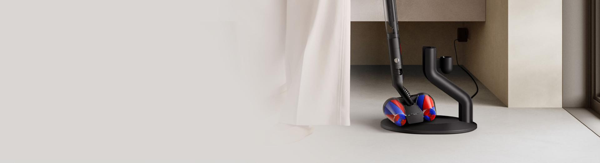 Vysavač Dyson PencilVac Fluffycones se vyjímá z magnetické nabíjecí stanice.