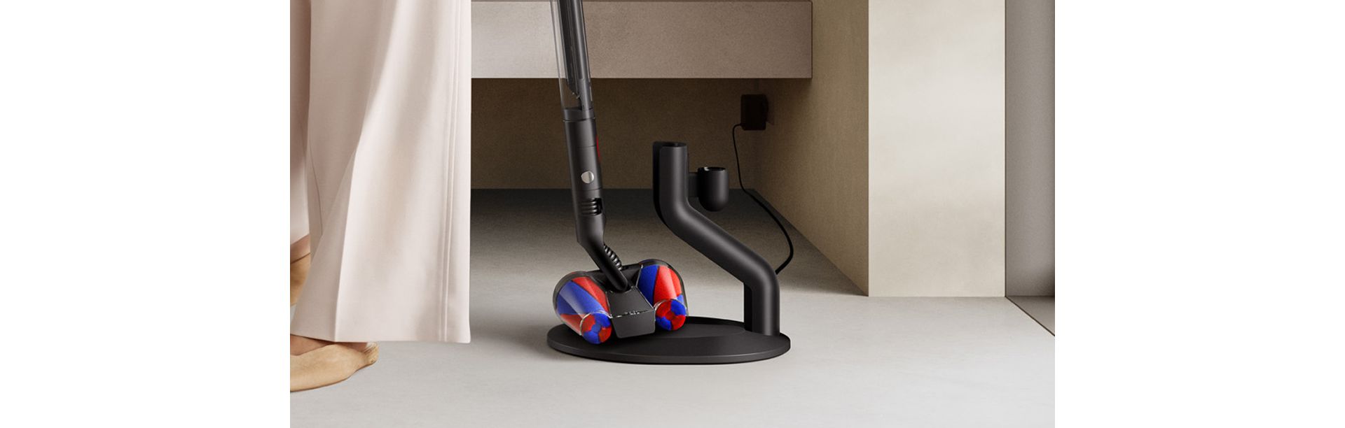 The Dyson PencilVac Fluffycones cleaner is retrieved from its magnetic charging dock.