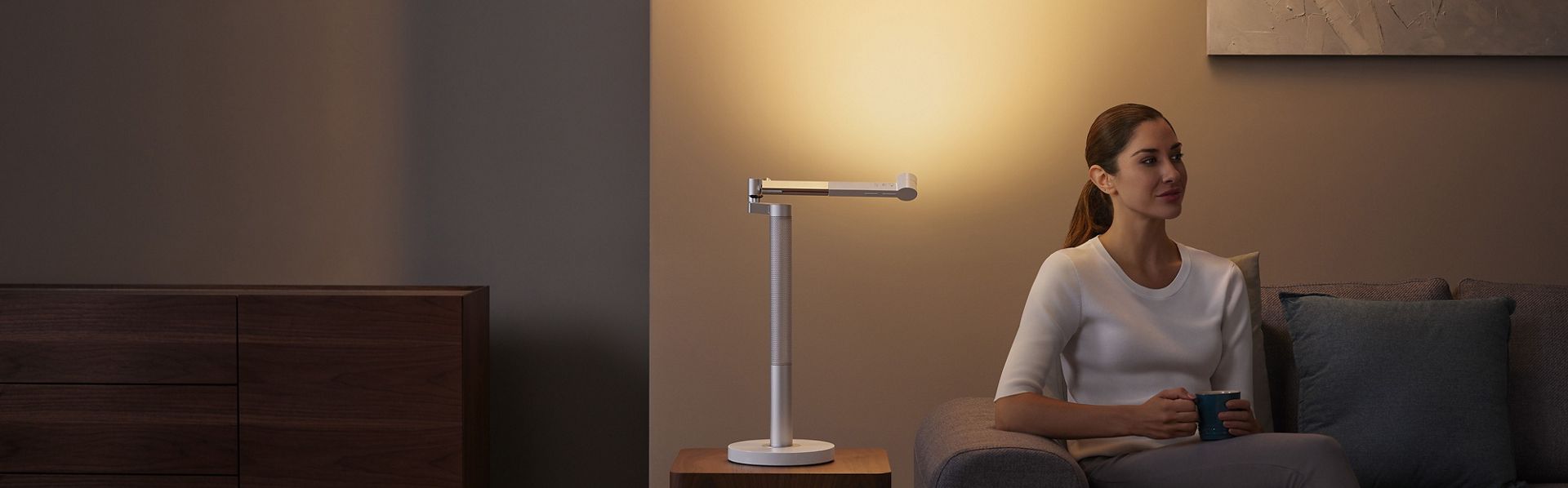 Woman basking in the glow of the Dyson Solarcycle Morph light