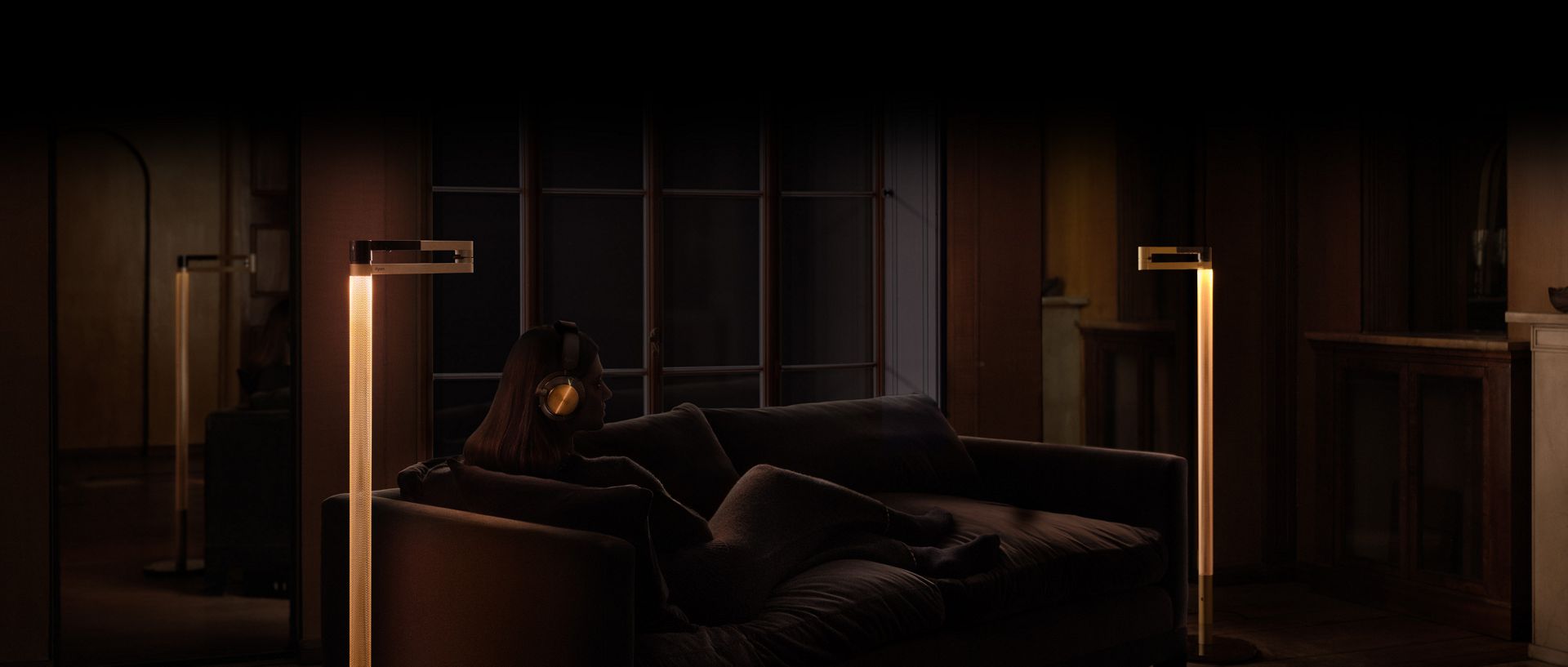 Owner of Dyson OnTrac headphones sat on the sofa with the Dyson Solarcycle Morph floor light.