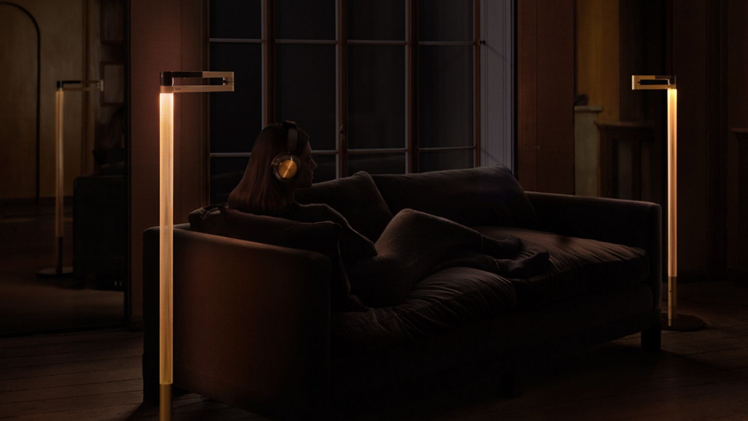 Owner of Dyson OnTrac headphones sat on the sofa with the Dyson Solarcycle Morph floor light.