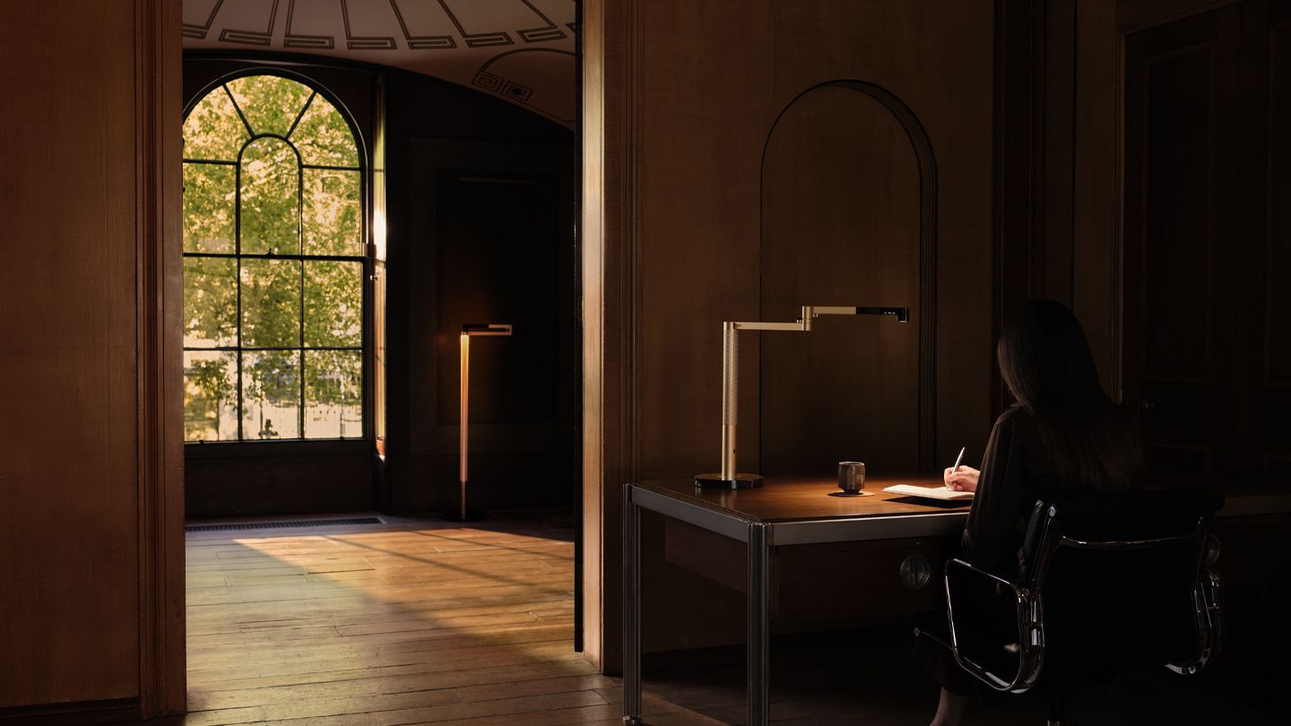 Owner sat at her desk doing work with the Dyson Solarcycle Morph desk light.