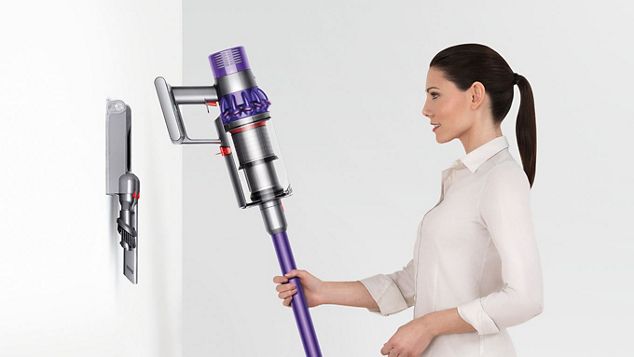 Donna che ripone ordinatamente Dyson Cyclone V10 nella stazione di ricarica