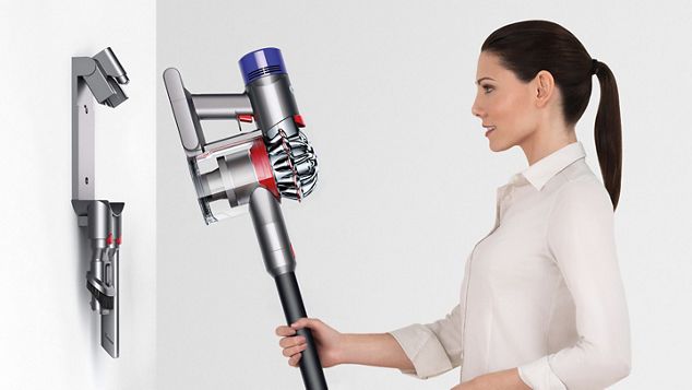 Frau setzt den Dyson V8 Staubsauger wieder in die Wandhalterung mit Ladefunktion ein