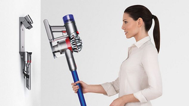 Une femme plaçant l’aspirateur Dyson V8 sur sa station de charge