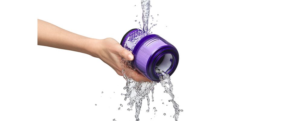 The filter of the Dyson V9 vacuum is rinsed under a stream of water.