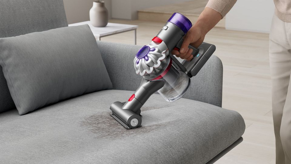 A Dyson Car+Boat vacuum cleaner is used with the Mini motorised head to deep clean sofa cushions.