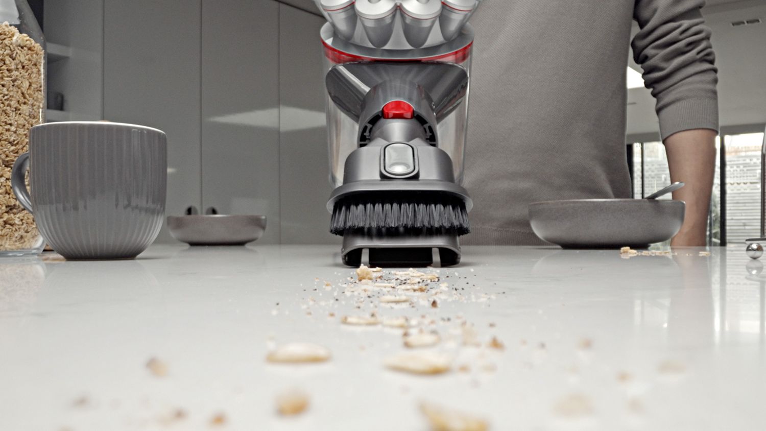 The Dyson Car+Boat handheld vacuum with the Combinationton tool cleaning mess from a kitchen counter.