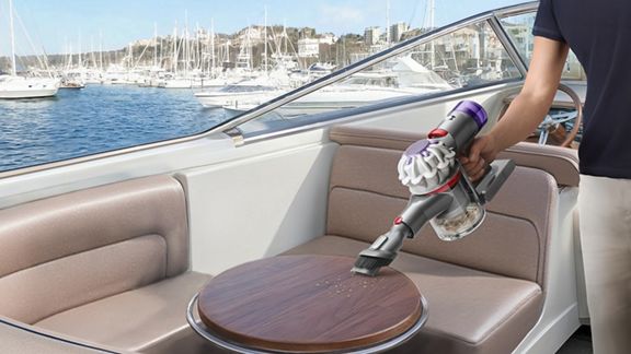Der Dyson Car+Boat Handstaubsauger mit der Kombi-Fügendüse reinigt einen Bootstisch von Schmutz.