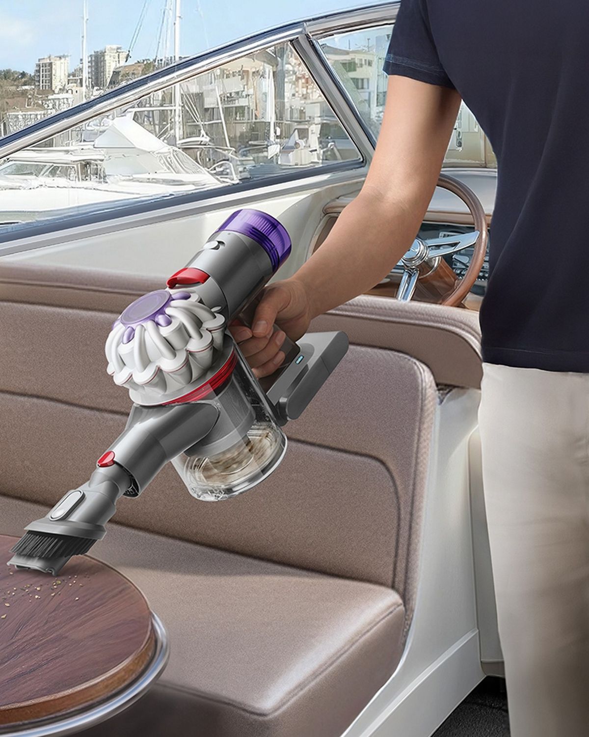 The Dyson Car+Boat handheld vacuum with the Combinationton tool cleaning mess from a boat table.