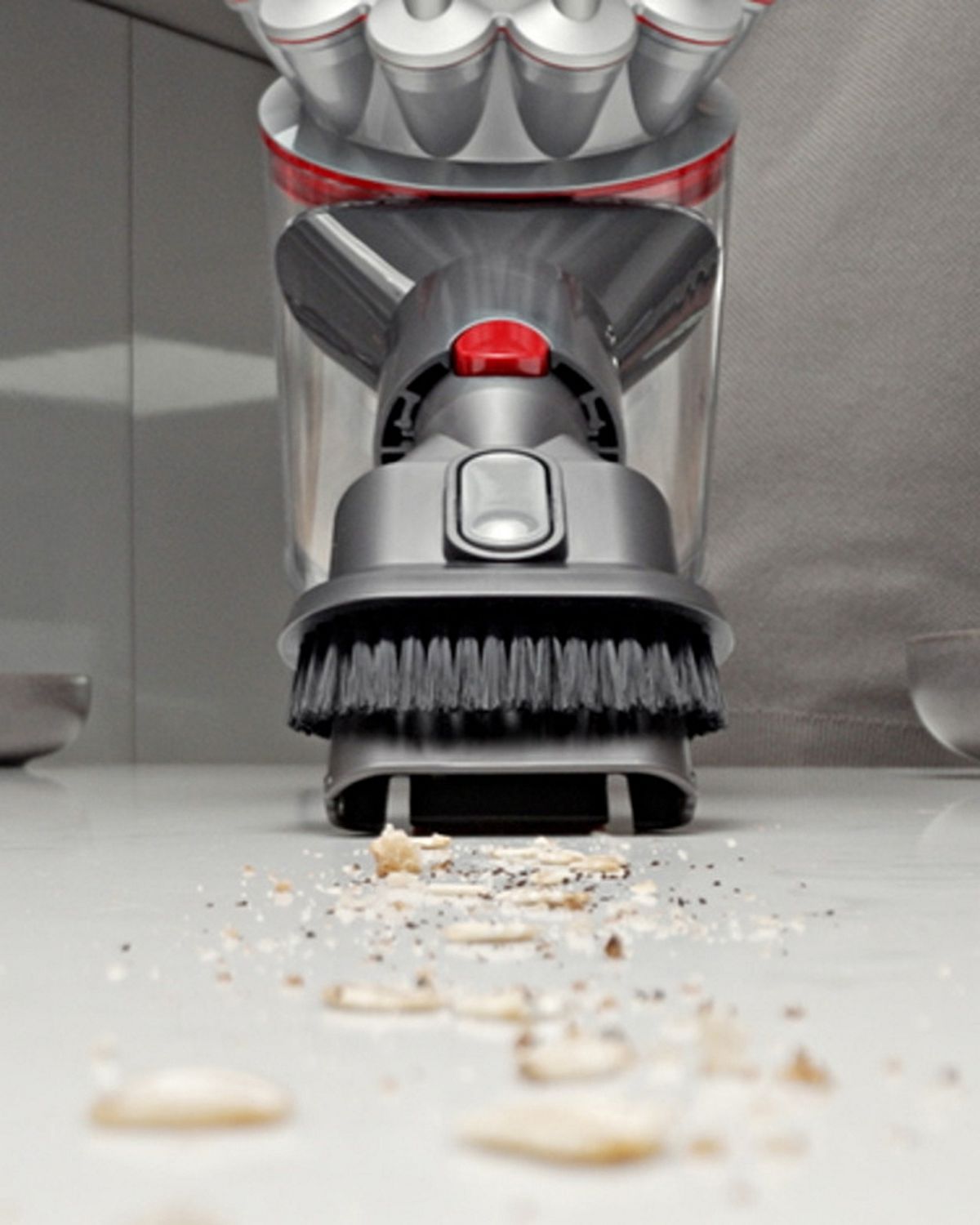 A Dyson Car+Boat handheld vacuum is used to clean a kitchen.