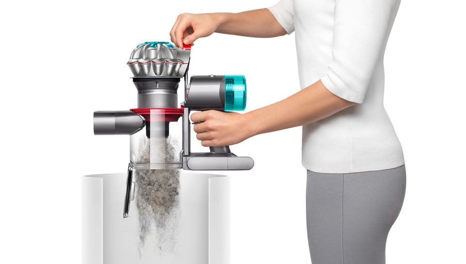 L’aspirateur Dyson V8 en train d’être vidé dans une poubelle.