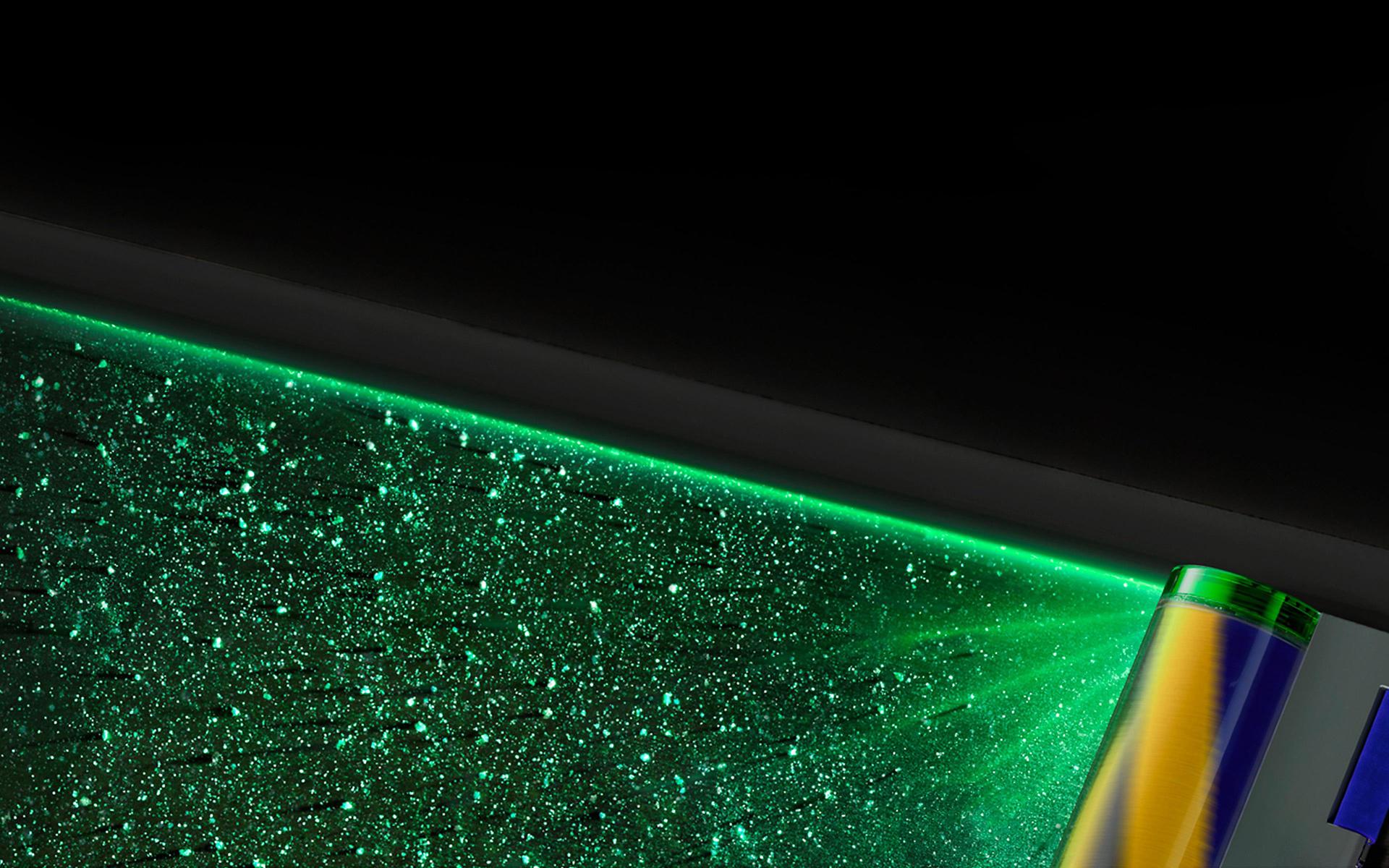 Zbliżenie na zielone światło lasera, uwidaczniające niewidoczny na pierwszy rzut oka kurz