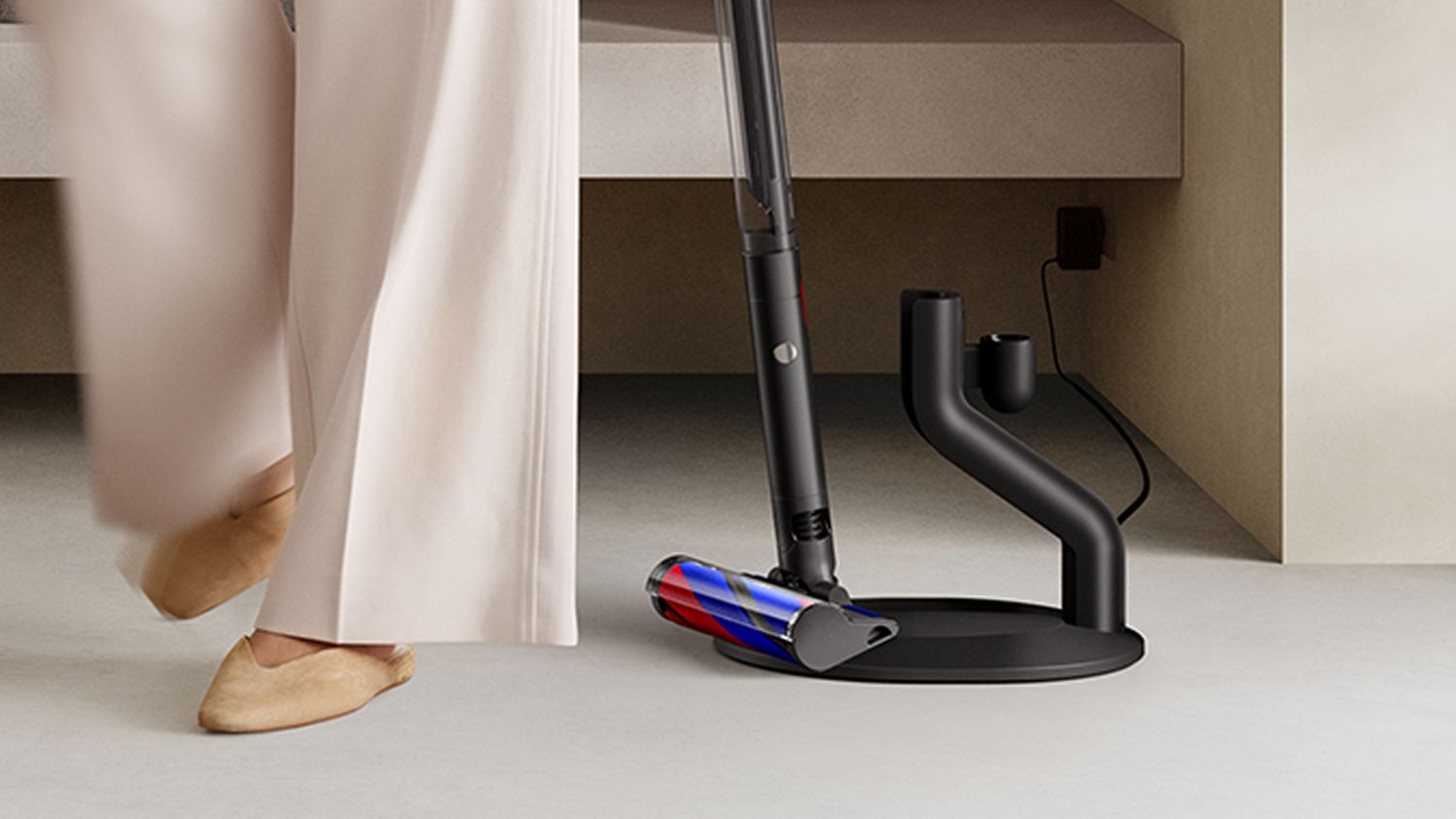 The Dyson PencilVac Fluffy cleaner is retrieved from its magnetic charging dock.