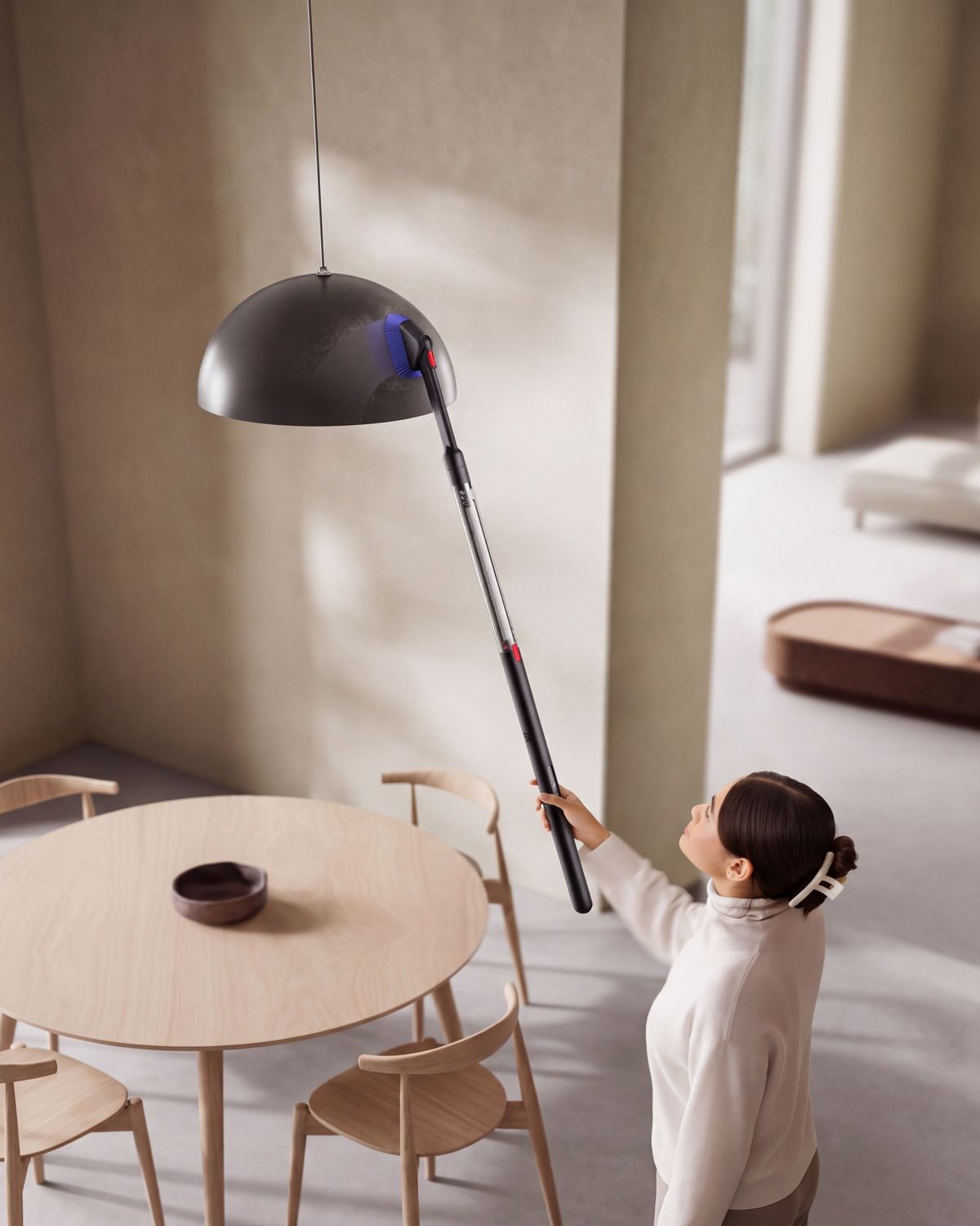 The Dyson PencilVac cleaner is used with the Rotating combi-crevice tool to clean a ceiling-mounted light.