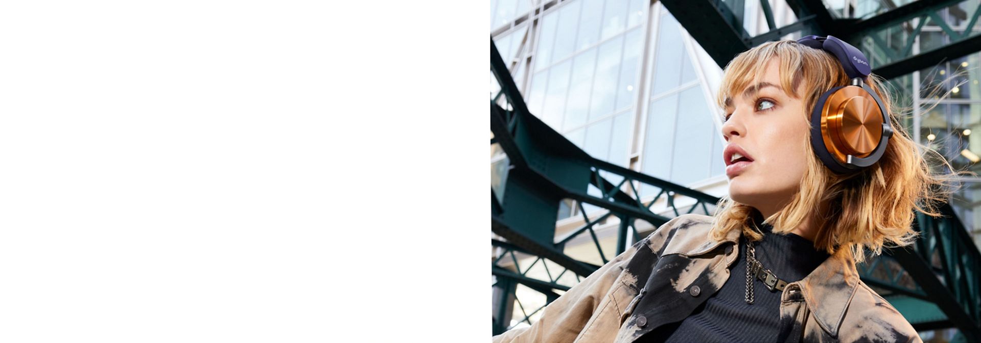 A model wearing Dyson OnTrac headphones with CNC copper outer caps while outside a modern building.