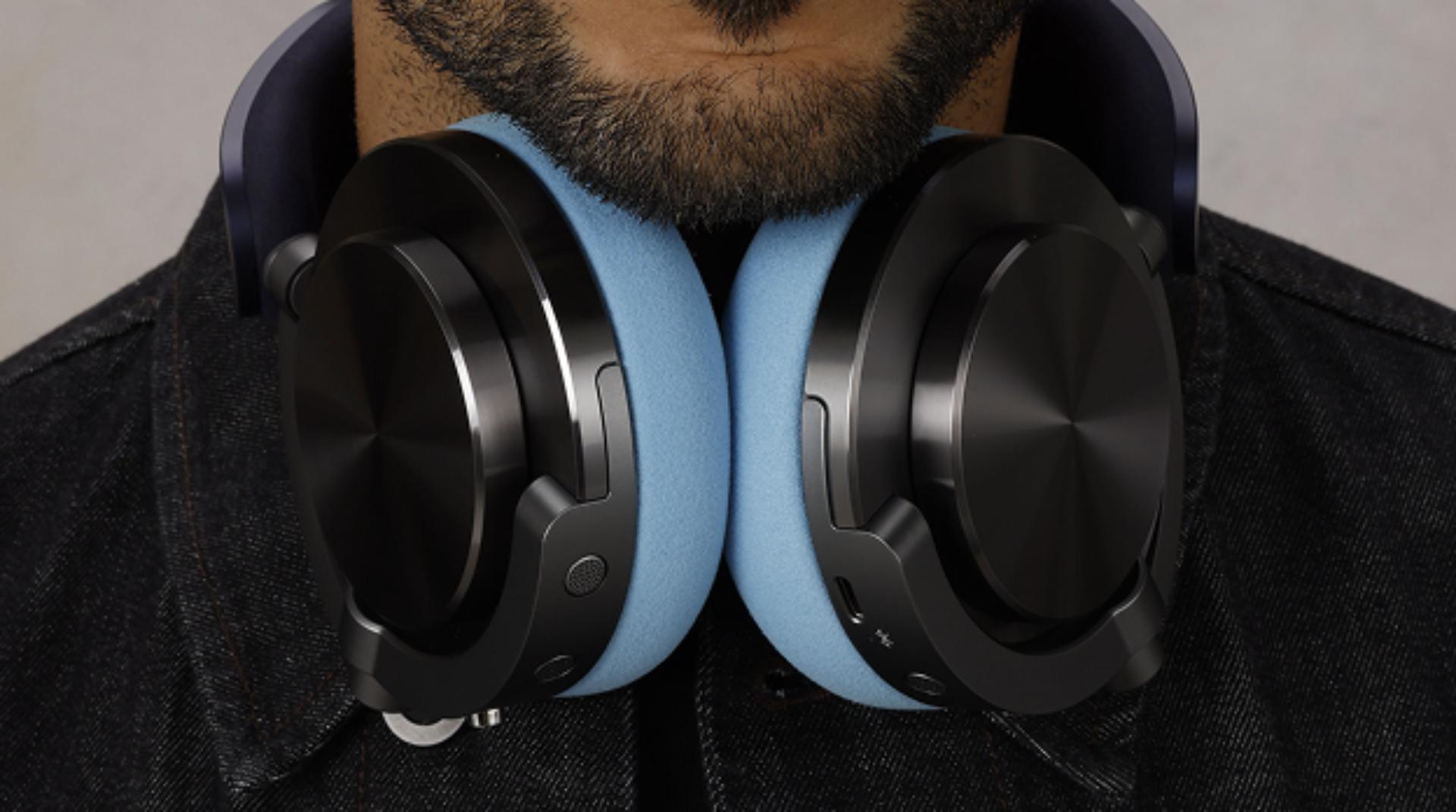 A model wearing Dyson OnTrac headphones, with CNC Black nickel outer caps, around their neck.