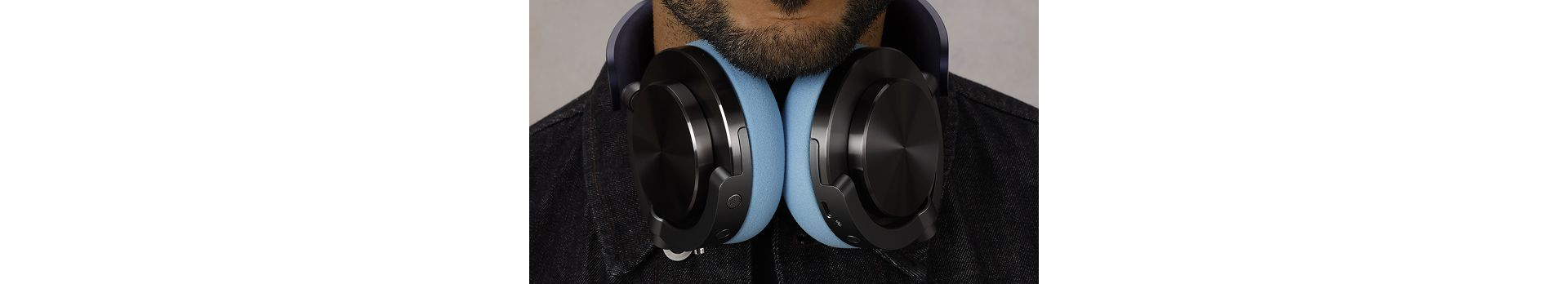A model wearing Dyson OnTrac headphones, with CNC Black nickel outer caps, around their neck.
