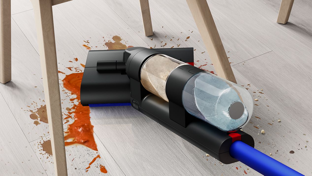 The Dyson WashG1 wet cleaner removing large food spills under a dining chair