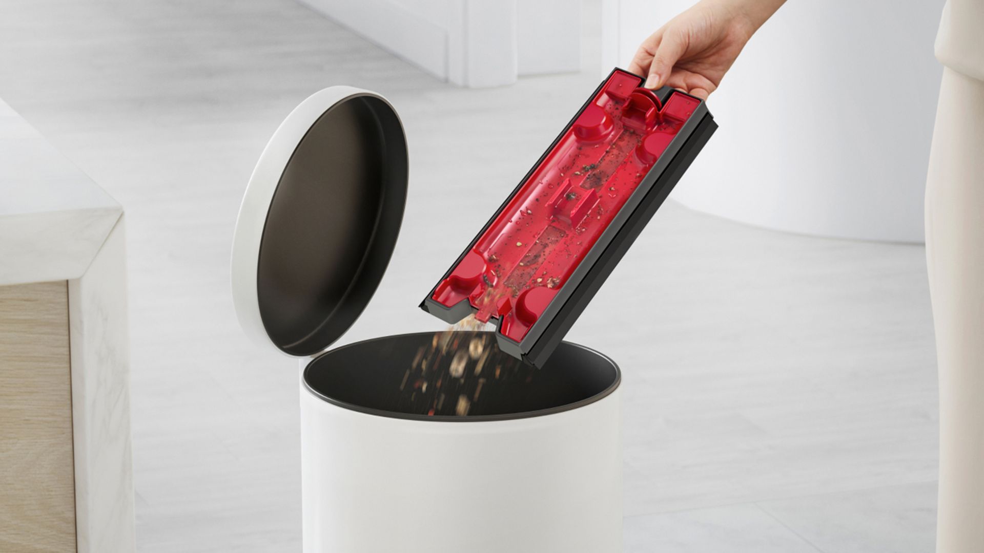 A user's hand emptying the debris into a bin The Dyson Wash G1 debris tray emptying into a bin