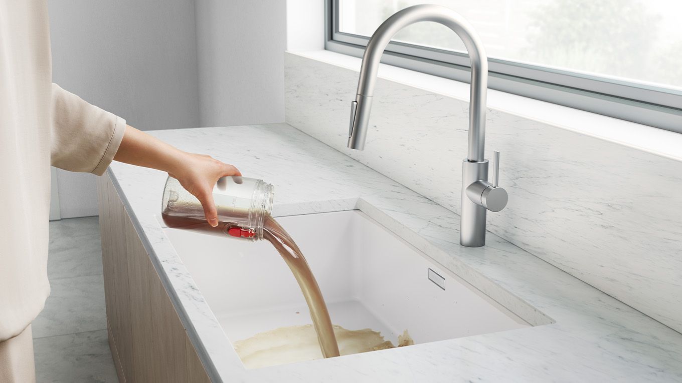 A user emptying the dirty water tank down a sink Dyson WashG1 dirty water tank being emptied down a sink