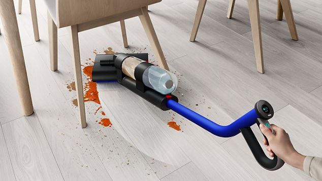 The Dyson WashG1 cleaning a large food spilage from under a dining table
