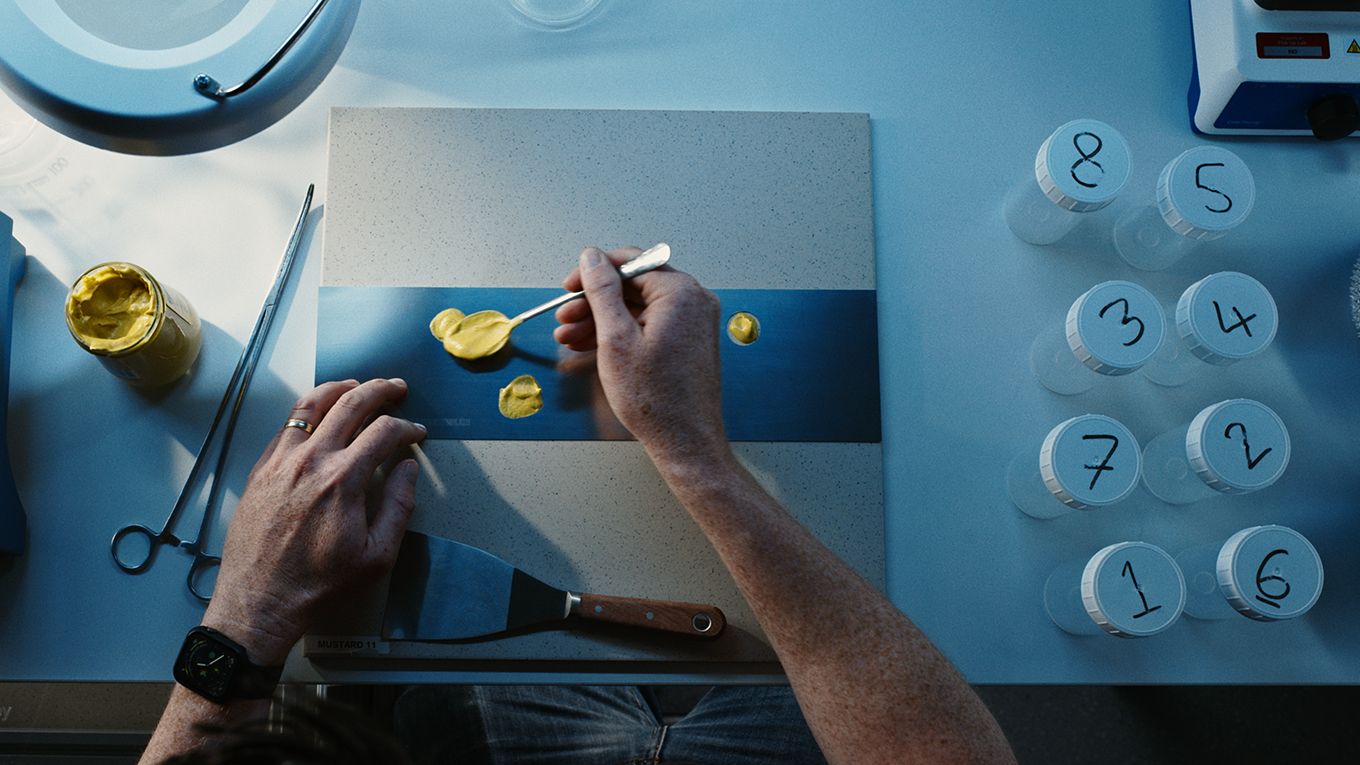 Yellow substance being applied to a surface, with other number jars to the side.