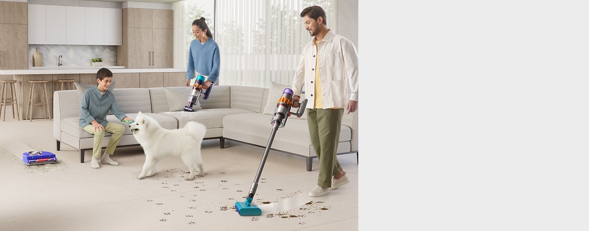 En gutt med en hund i en stue, mens foreldrene bruker Dyson-teknologi for å fjerne søl fra kjæledyr, og en robot som støvsuger hele rommet