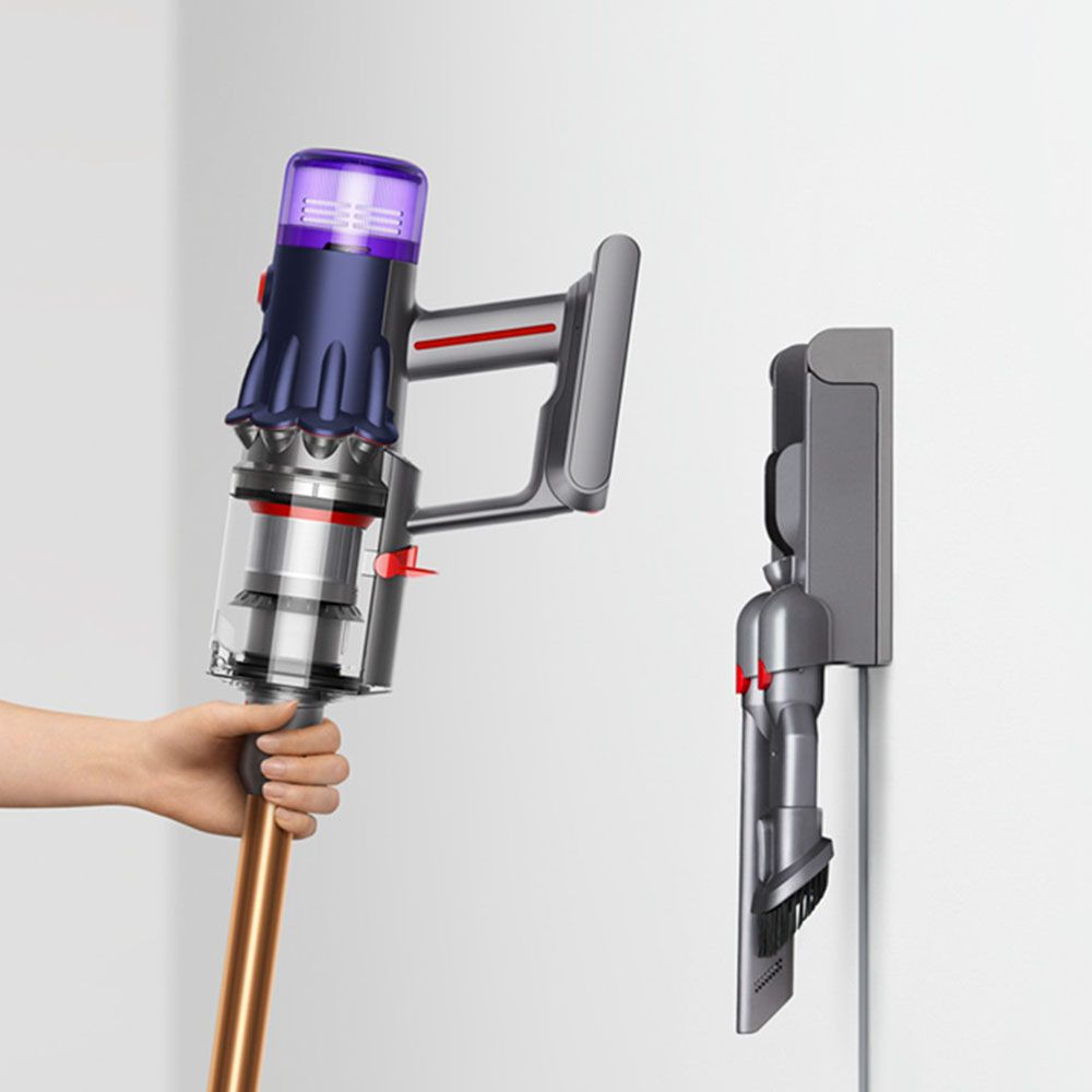 A Dyson vacuum being lowered into a docking station or dock.