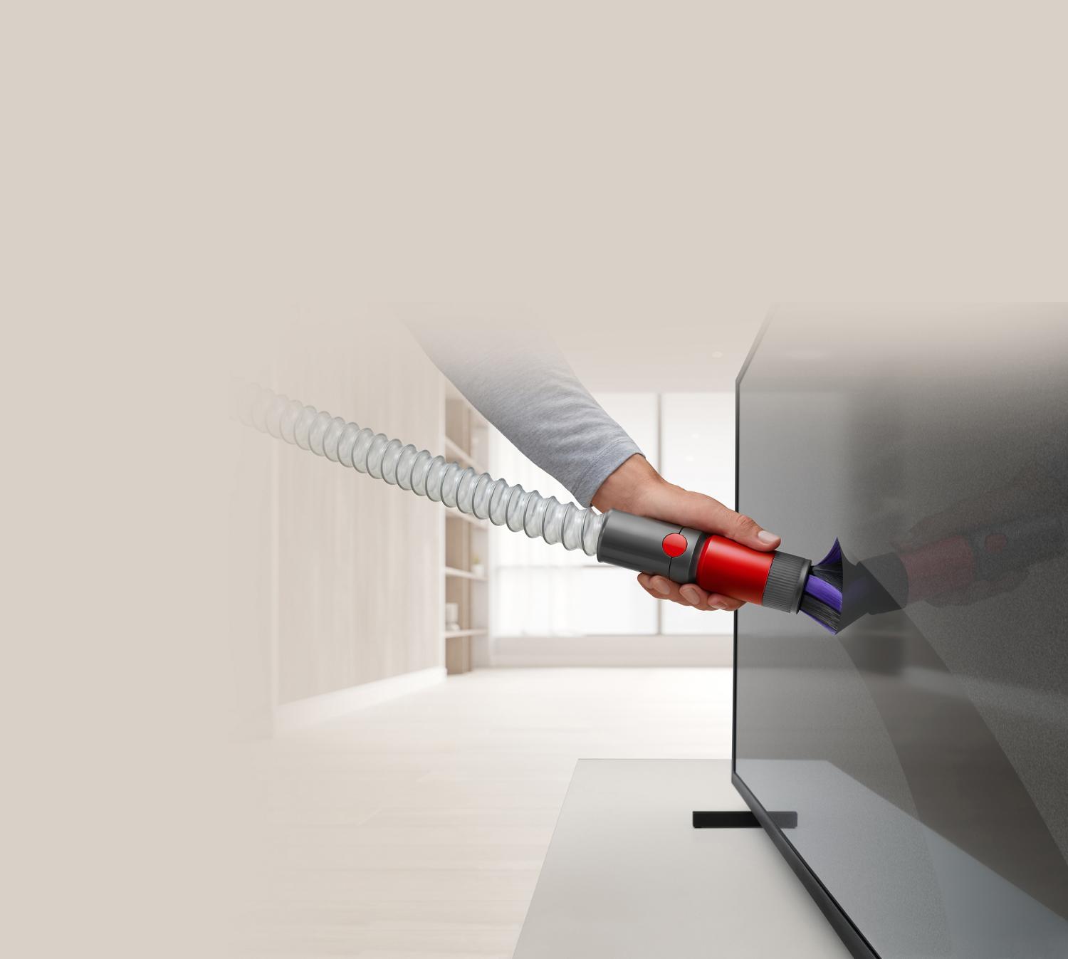 Cepillo de limpieza antiarañazos y manguera de extensión limpiando un televisor.