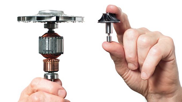 Eine Hand hält einen großen Motor, während eine andere einen deutlich kleineren Dyson Motor hält.